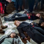 A foto mostra protestantes performance um "Die in". A manifestação é contra a família Sackler, ligado à Purdue Pharma, produtora do Oxy Contin. Em meio aos protestantes está a fotógrafa Nan Goldin, rodeada por papéis que dizem "Sackler Lie People Die" e frascos de remédio