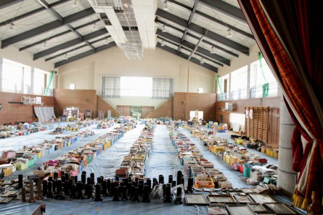 Na foto, vemos o ginásio de uma escola, na parte mais ao sul da prefeitura de Miyagi, repleto com caixas de fotografias e outros pertences resgatados pelo SDF