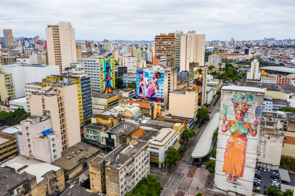 Foto panorâmica do centro de BH, que mostra algumas empenas pintadas nas edições do CURA, inclusa a obra de Criola