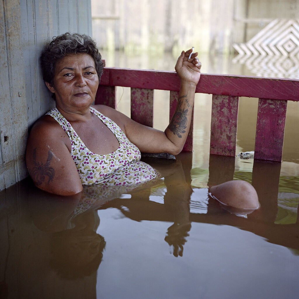 From "Submerged Portraits" by Gideon Mendel: "It often floods here, almost every year, so most of our homes are on stilts. But nobody can remember a higher flood. We are all camping now. We have no choice but to be in the water, even though the snakes make it dangerous. I’ve heard the government has plans to move us away and turn this area into a park. But I’ve heard this for years and we are still here. It’s not a big deal: when the floods come, we take our stuff and leave for a while". Francisca Chagas dos Santos, Rio Branco, Brazil, 10 March 2015.