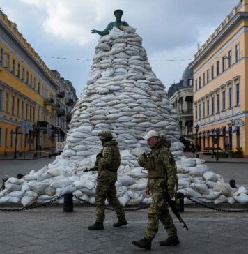 Soldados caminham por monumento coberto por sacos de areia em Odessa, na Ucrânia, em meio à invasão da Rússia. Foto: Alexandros Avramidis/Reuters