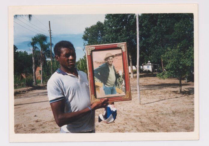 Seu Jovenil segurando o retrato do seu tio, Otávio Caetano, mestre da cupópia e festeiro da comunidade, sem data. Quilombo Cafundó, 35ª Bienal de São Paulo. Cortesia: CEDAE - Centro de Documentação Cultural Alexandre Eulálio, Universidade Estadual de Campinas