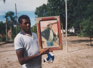 Seu Jovenil segurando o retrato do seu tio, Otávio Caetano, mestre da cupópia e festeiro da comunidade, sem data. Quilombo Cafundó, 35ª Bienal de São Paulo. Cortesia: CEDAE - Centro de Documentação Cultural Alexandre Eulálio, Universidade Estadual de Campinas