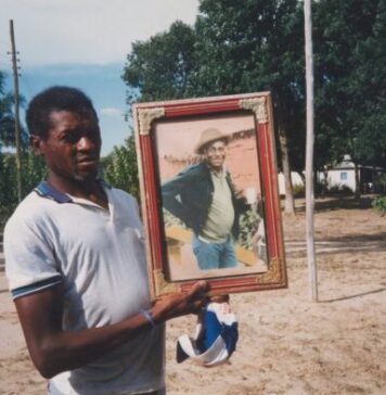 Seu Jovenil segurando o retrato do seu tio, Otávio Caetano, mestre da cupópia e festeiro da comunidade, sem data. Quilombo Cafundó, 35ª Bienal de São Paulo. Cortesia: CEDAE - Centro de Documentação Cultural Alexandre Eulálio, Universidade Estadual de Campinas